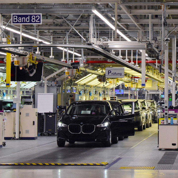 BMW production line with dark vehicles lined up one behind the other, slowly moving towards the viewer.