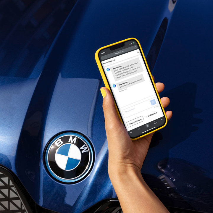 Smartphone in one hand above a blue BMW bonnet