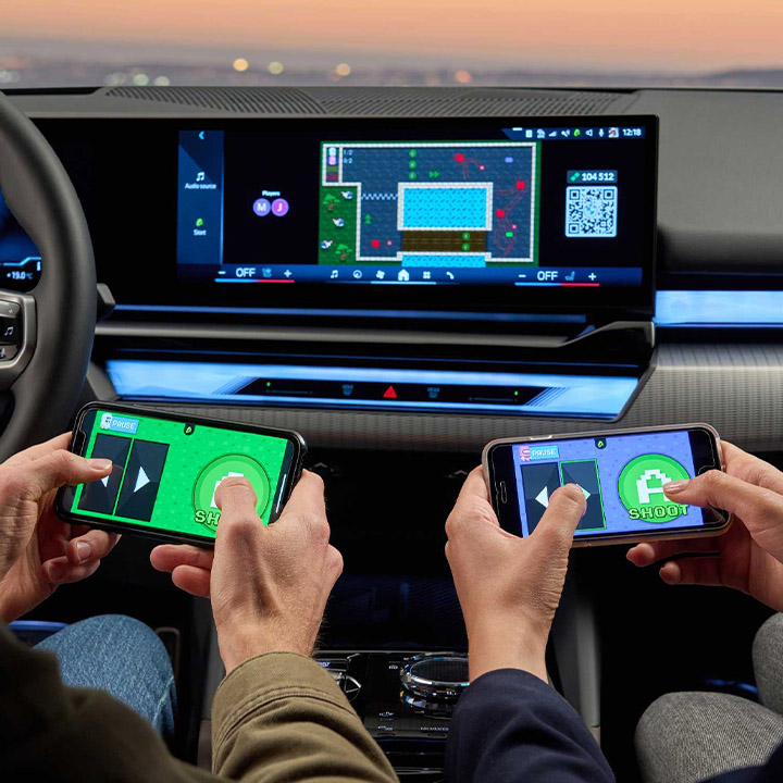 Drivers and passengers controlling a game on the curved display of a modern BMW using their smartphones.