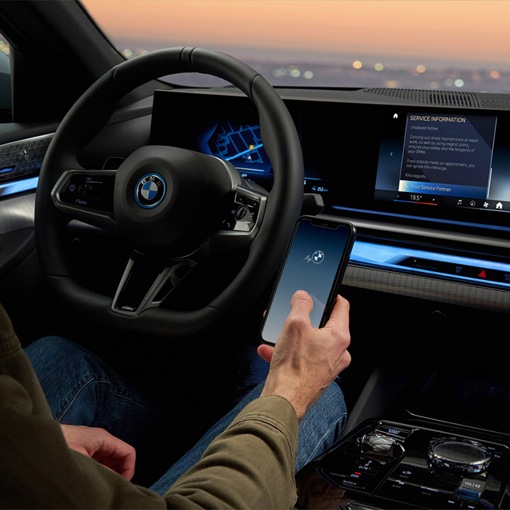 Shot from the back seat of a BMW driver who has just picked up his mobile phone to retrieve information.