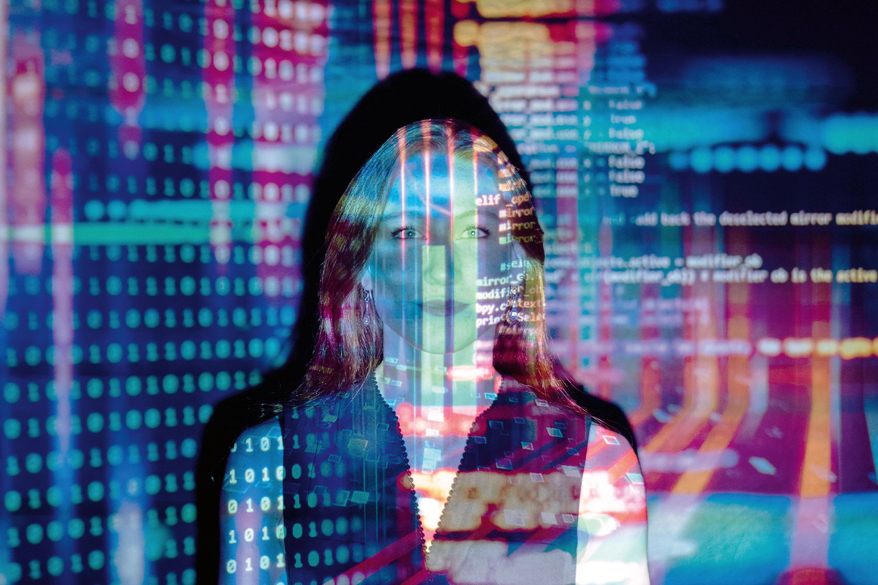 A woman standing infront of a wall projected with red and blue shapes.