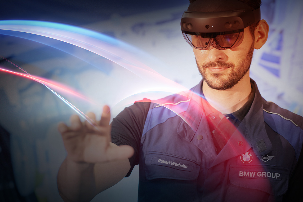 A BMW employee wearing safety goggles controls a computer or production facility using gestures.