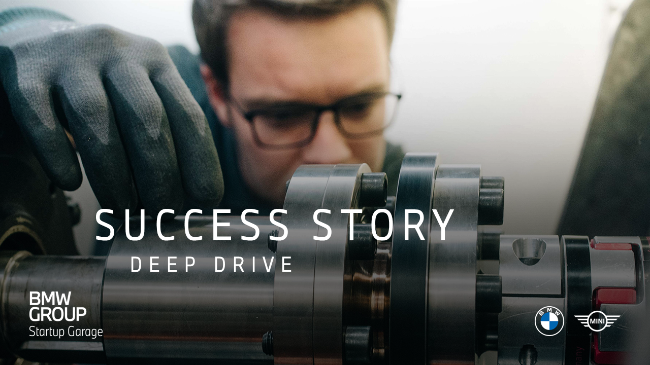 A person wearing gloves works closely with a large metal machine component in an industrial setting.