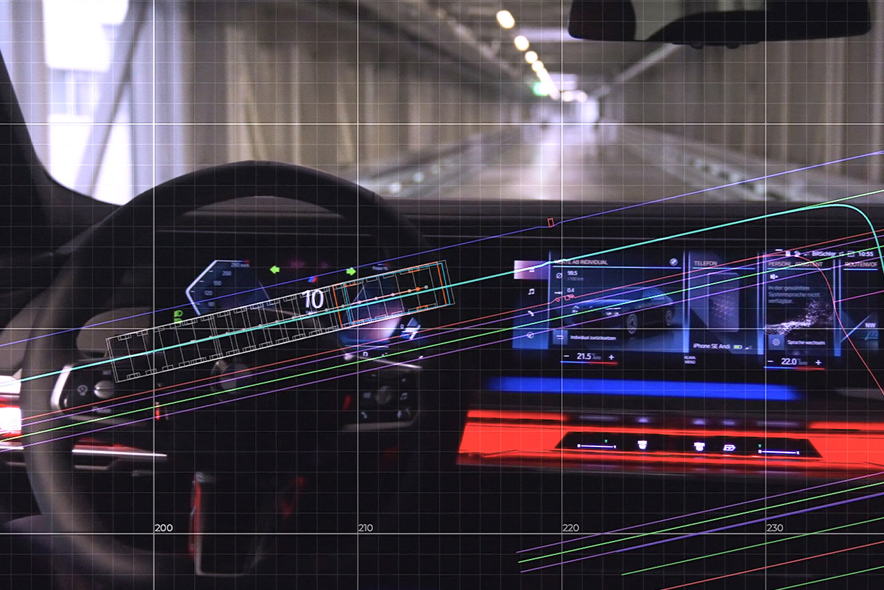 View over the steering wheel and curved display of a current BMW model driving through a tunnel.